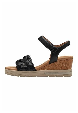Des sandales à talons compensés noires présentent un design de bride tissée, un talon en liège, une semelle intérieure beige et une bride de cheville en cuir. La semelle est de couleur marron clair avec un relief antidérapant.