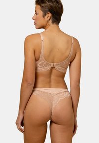 Ensemble de dentelle comprenant un soutien-gorge et un string dans des teintes nude douces, avec des motifs floraux, des bretelles ajustables et une fermeture à clip au dos.