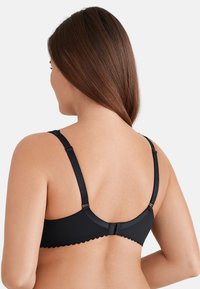 Senza fili nera con spalline regolabili, bordi ondulati e chiusura con gancio. Presenta una superficie liscia e un design semplice e classico.