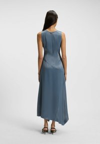 Maxikleid aus weichem blauen Satin mit ärmellosem Design, leicht ausgestelltem Saum und einem dezenten Reißverschluss auf der Rückseite zur Verschluss.