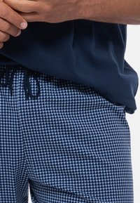 Marineblaue Baumwoll-Lounge-Shorts mit einem kleinen karierten Muster in Hellblau. Verfügt über einen verstellbaren Kordelzugbund und einen lockeren Schnitt.