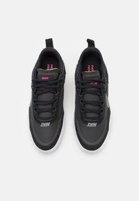 Svarte Nike sneakers laget av mesh og syntetiske materialer, med en hvit såle, teksturerte detaljer og rosa merkevare på tungen og siden.
