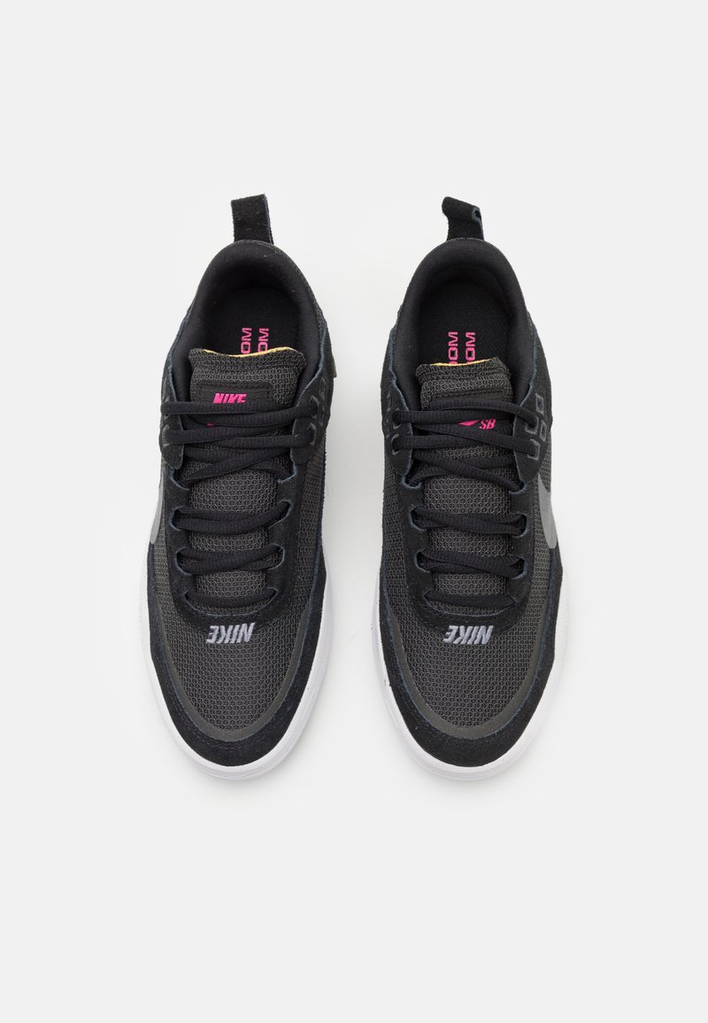 Zapatillas Nike negras hechas de malla y materiales sintéticos, con una suela blanca, acentos texturizados y marca en rosa en la lengüeta y el lado.