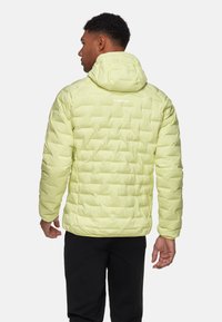 Lys gul pufferjakke med hætte, der har en quiltet tekstur, elastiske manchetter og et diskret logo på ryggen.