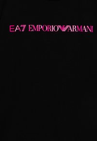 Čierne tričko s logom "EA7 EMPORIO ARMANI" v tučnom, jasnom ružovom písme, so horizontálnymi pruhmi a stilizovanou ikonou orla.