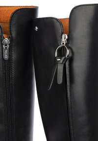 Stivali neri in pelle fino al ginocchio con una superficie liscia, dotati di una zip argentata, un cordoncino in pelle e una fodera interna beige.