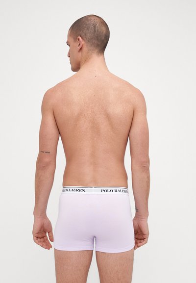 Boxer-briefs blancs avec un waistband noir portant l'inscription "POLO RALPH LAUREN", design ajusté, texture lisse et léger éclat visible sur le tissu.