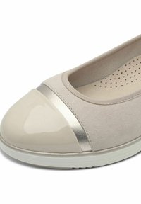 Ballerines beiges avec un bout arrondi brillant de couleur beige clair, accent métallisé et tige texturée. Doublure douce avec des perforations pour la respirabilité.
