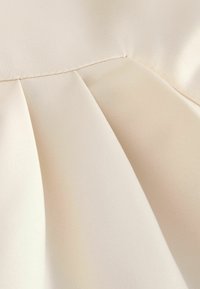 Heled beež kangas su siledaga tekstuuriga, millel on volditud disain ja nähtavad õmblustäied ääres.