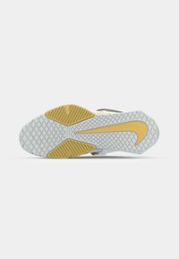 Suela de zapato de goma blanca texturizada, con acentos amarillos y un diseño ondulado. El patrón de agarre incluye formas de diamante y líneas.