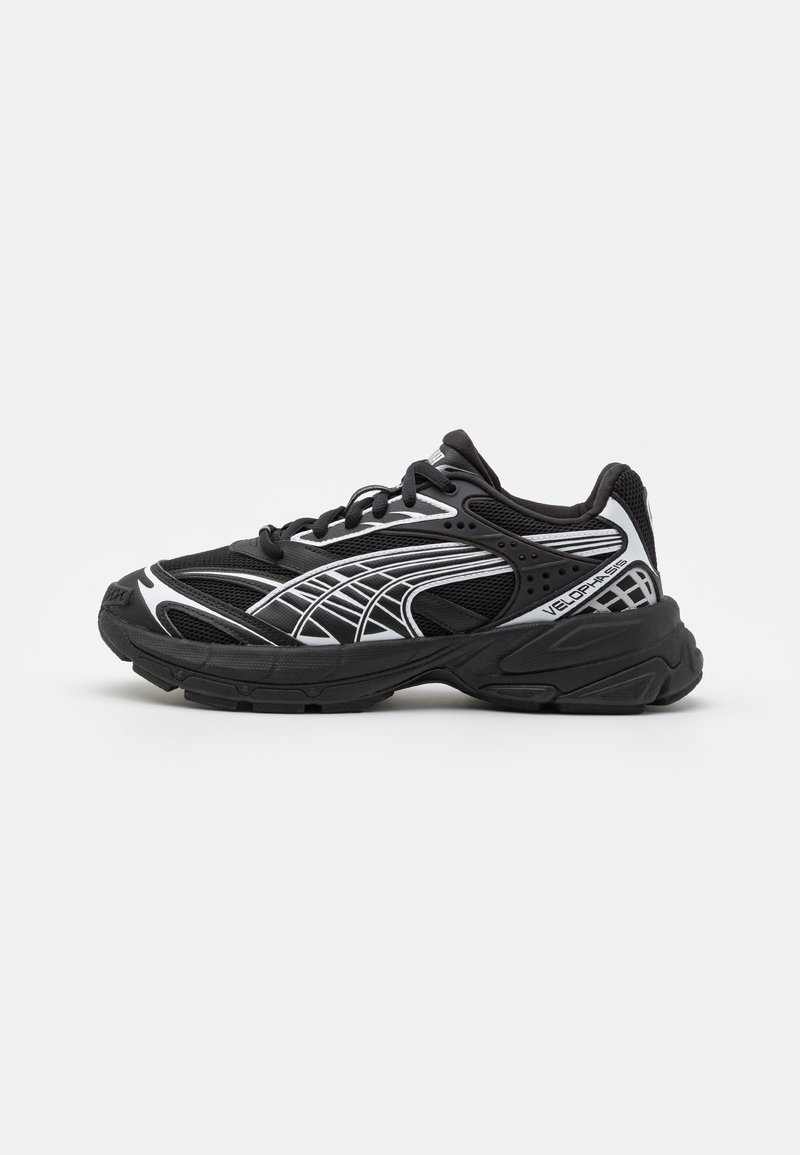 Chaussure de sport noire avec un matériau en mesh et synthétique, présentant des accents blancs, une semelle rembourrée et un motif de grip texturé.