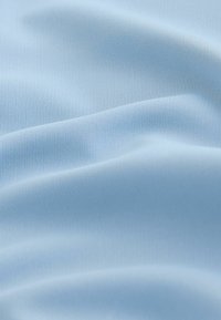 Lyseblåt stof med en glat, blød tekstur og subtil glans, fremviser bløde folder og krusninger over det hele.