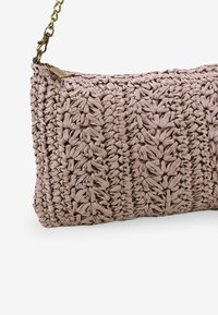 Borsa a tracolla rosa intrecciata con motivo strutturato, dotata di una tracolla in catena dorata e zip. Forma rettangolare compatta, realizzata in fibre naturali.