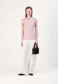 Light pink sleeveless tank top, white wide-leg pants, black shoes, and a small black bag with two handles. Simple design and minimal texture.