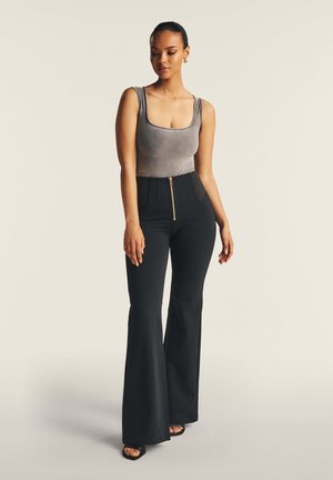 Pantaloni neri a zampa d'elefante con vita alta e dettagli in zip dorato abbinati a un top grigio aderente con scollatura testurizzata.