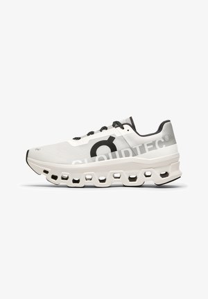 Baskets de course blanches avec un dessus en mesh, des accents noirs, une semelle rembourrée dotée de découpes hexagonales et un marquage "CLOUDTEC".