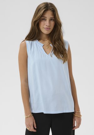 Lyseblå ærmeløs top med V-hals og flæsekanter ved halsen. Blødt stof med glat tekstur, kombineret med sorte bukser.