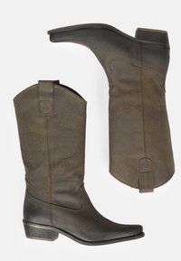 Botas de vaquero de cuero marrón con punta afilada, caña inclinada y tacón apilado. Presentan costuras decorativas y lengüetas para facilitar su uso.