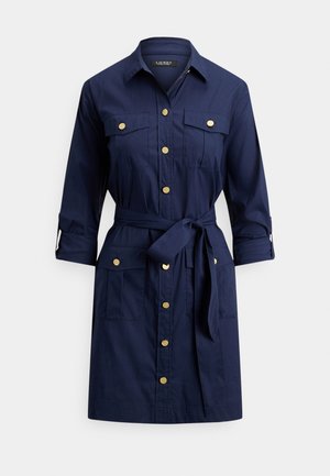 Haljina-košulja tamnoplave boje s brončanim gumbima, pojasom za vezanje u struku, dugim rukavima s kopčama i četiri džepa s preklopom.