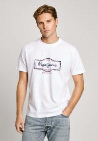 White cotton t-shirt featuring a central navy and pink logo design that reads "Pepe Jeans" with a rectangular border. Short sleeves, crew neck.