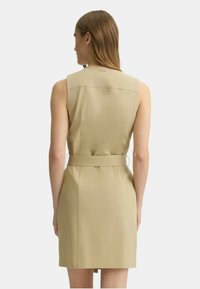 Abito beige senza maniche con vita aderente, gonna dritta e dettaglio della cintura sul retro. Tessuto liscio con un design pulito e minimalista.