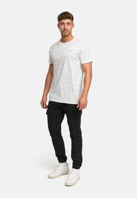 Grau gesprenkeltes T-Shirt, Rundhals, kurze Ärmel, kombiniert mit schwarzen engen Cargo-Hosen und weißen Sneakers. Einfaches und lässiges Design.