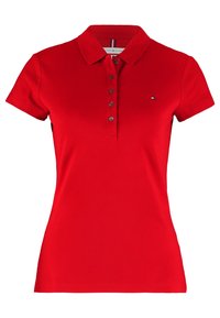 Czerwona koszulka polo damska z krótkim rękawem, kołnierzykiem, pięcioma czarnymi guzikami i małym logo Tommy Hilfiger po lewej stronie klatki piersiowej.