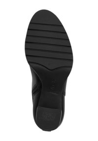 Semelle de chaussure noire en caoutchouc texturé, avec des rainures horizontales pour l'adhérence, un bout arrondi et un logo sur la zone du talon.