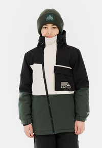 Jakna s crno, krem i zelenim blokovima boja, sa patentnim zatvaračem sprijeda, visokim ovratnikom i džepom na prsima. Pleteni zeleni beanie s logotipom. Glatka tekstura.