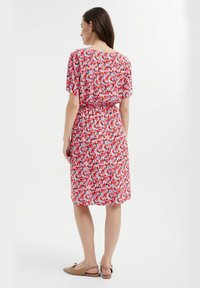 Blumenkleid mit kurzen Ärmeln, tailliert, in Rot-, Pink- und Blautönen auf weißem Hintergrund; weicher, leichter Stoff.