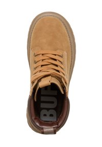 Bottine en daim beige avec accents en cuir marron, lacets ronds, col rembourré et semelle en caoutchouc texturée. Présente un logo de marque bien visible à l'intérieur.