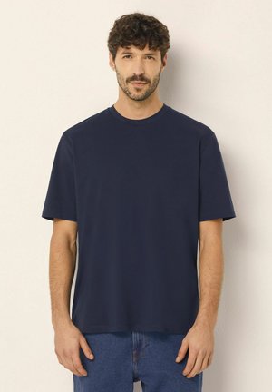 Tricou din bumbac de culoare albastru marin, cu mâneci scurte, de tip crew, și un croi lejer, având o textură fină și fără modele vizibile.