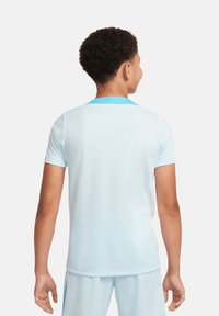 Maglia sportiva azzurra chiaro con maniche corte, texture in rete, colletto rotondo e accenti turchesi a contrasto sul collo e sui lati.