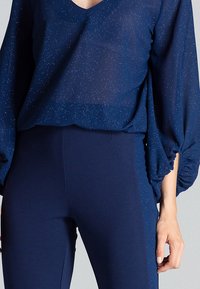 Granatowa, przezroczysta bluzka z dekoltem w serek i drobnym połyskiem, w zestawieniu z wysokimi granatowymi legginsami o prostym kroju.