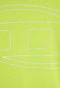Tessuto verde neon con linee ricamate bianche che formano forme rettangolari e curve, che mette in evidenza una texture liscia.