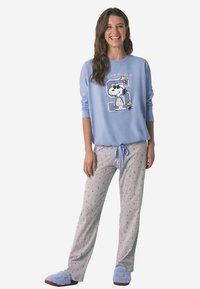 Lichtblauwe sweatshirt met Snoopy-afbeelding, grijze pyjamabroek met kleine blauwe patronen en blauwe, pluizige pantoffels. Casual loungestyleset.