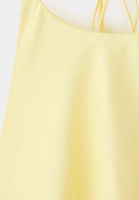 Robe sans manches jaune clair avec fines bretelles doubles sur fond blanc.