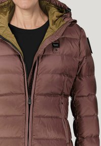 Giubbotto imbottito marrone con interno verde, dotato di zip frontale, tasche laterali e cappuccio. Texture liscia con sezioni trapuntate.