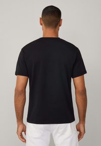 Schwarzes Kurzarm-T-Shirt mit Rundhalsausschnitt. Glattes Baumwollmaterial, normale Passform. Schlichtes Design, ohne sichtbare Logos oder Muster.