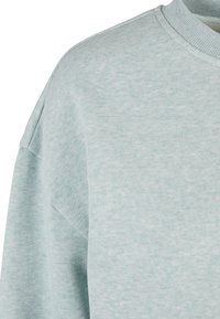 Sweat-shirt bleu clair à col rond avec col côtelé et couture d'épaule visible en tissu doux et texturé.