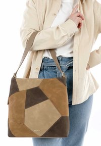 Bolso de ante en tonos marrón y beige con un diseño de patchwork geométrico, que cuenta con una correa para el hombro y acentos de metal.
