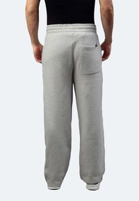 Graue Baumwoll-Sweatpants mit elastischem Bund, einer Gesäßtasche und lockerer Passform. Der Stoff hat eine weiche Textur und einen leichten Stretch.