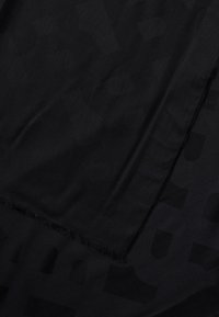 Bufanda de tela negra con textura suave y un sutil patrón tonal. Los bordes están cuidadosamente rematados con flecos, añadiendo un detalle decorativo.