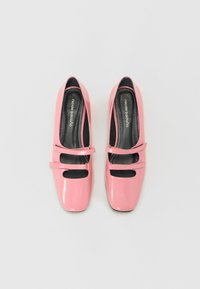 Sapatos de salto alto em verniz rosa com bico quadrado e duas tiras ajustáveis na parte superior. Solas interiores pretas com detalhe do logótipo. Textura suave.