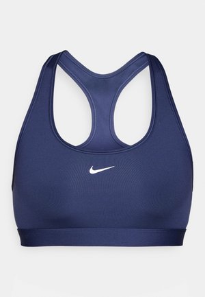 Marinblå sportbehå i mjukt, stretchigt material med racerback-design. Har en vit Nike-logotyp på framsidan, vilket ger en åtsittande passform.