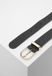 Cinturón de cuero negro con un acabado texturizado y hebilla rectangular dorada, que cuenta con múltiples agujeros para ajuste.