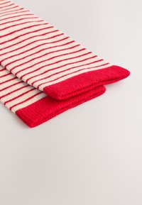 Rot-weiß gestreifte Socken mit gerippten roten Bündchen. Weiche Textur mit Strickmuster. Ansicht von der abgeschnittenen Seite mit gefalteten Kanten.