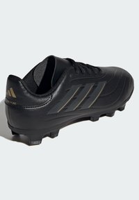 Zapato de fútbol negro con empeine de cuero liso, paneles texturizados y tres franjas doradas angulares. Presenta un diseño de corte bajo y suela con tachuelas.