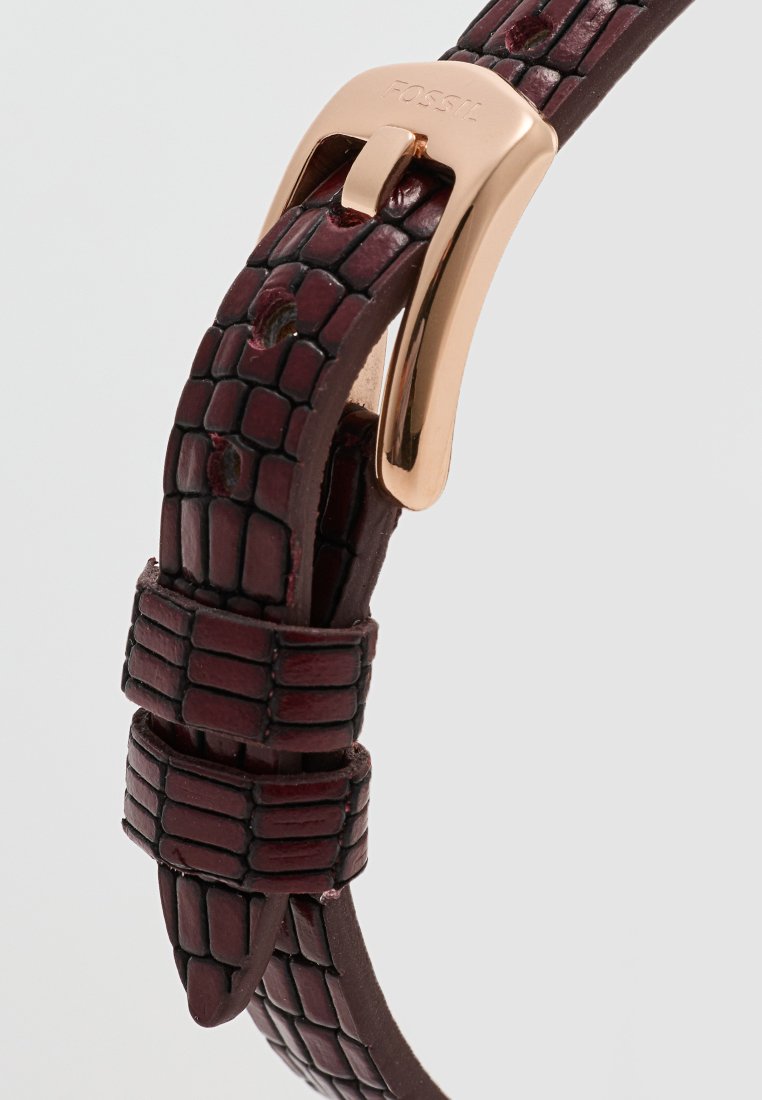 Correas de reloj de cuero burdeos con un diseño texturizado y estampado, que cuenta con un cierre de metal dorado con detalles de logotipo grabados.