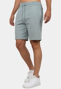 Lichtblauwe sportshorts met een elastische tailleband, aanpasbare koord en zijzakken. Voorzien van subtiele merkstiksels op het been.